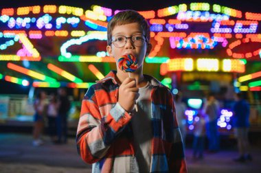 Beyaz bir çocuk, bir çocuk, eğlence parkına eğlenmek, oynamak ve atlıkarıncaya binmek için geldi. Atlıkarıncanın önünde duran bir çocuk.