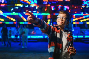 Beyaz bir çocuk, bir çocuk, eğlence parkına eğlenmek, oynamak ve atlıkarıncaya binmek için geldi. Atlıkarıncanın önünde duran bir çocuk.