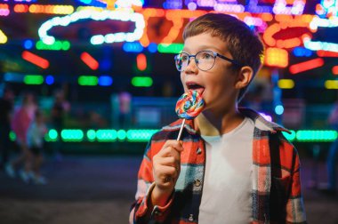 Beyaz bir çocuk, bir çocuk, eğlence parkına eğlenmek, oynamak ve atlıkarıncaya binmek için geldi. Atlıkarıncanın önünde duran bir çocuk.