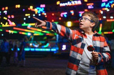 Yakışıklı ve mutlu bir çocuk lunaparkta eğleniyor..