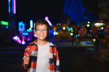 Mutlu çocukluk ve tatil kavramı. Sevimli bir çocuk eğlence parkında mutlu bir şekilde vakit geçirir..