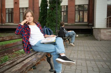 Çocuklar okul bahçesinde bankta oturarak kitap okurlar. Okula dönelim. Okul derslerinin başlangıcı..