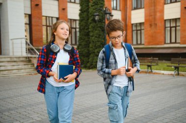 Okul bahçesinde duran gülümseyen okul çocuklarının portresi..