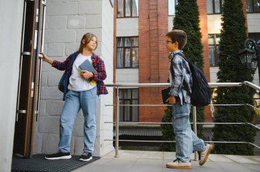 Çocuklar okula giriyor, büyük ahşap kapıyı açıyorlar. Güneşli bir günde okul kapısında sırt çantalı çocuklar. Akademik yılın başlangıcında. Seçici odaklı resim