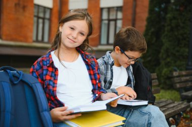 School friends, a boy and a girl spend time together near the school. Back to school. clipart