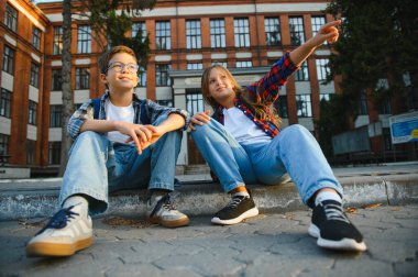 Okulun yakınındaki mutlu okul çocukları. Bir erkek ve bir kız ilkokul öğrencisidir. Okul arkadaşlığı.