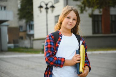 Okula geri dönen bir kız, okula sırt çantası ya da çantasıyla ve ellerinde kitaplarla gidiyor. Eylül 'de okula yakın bir kız öğrenci..