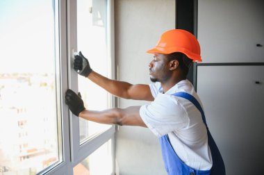 İnşaat alanındaki pencere kurulumunda çalışan erkek sanayi işçisi