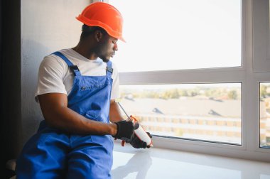 İnşaat alanındaki pencere kurulumunda çalışan erkek sanayi işçisi