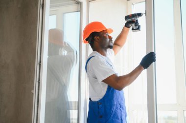 Evdeki oturma odasına plastik pencereler monte eden ya da ayarlayan işçi.