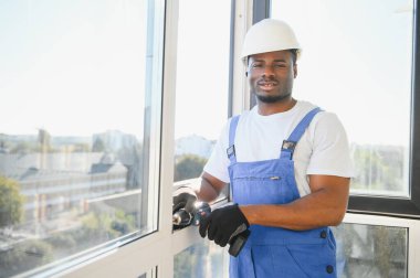 Yakışıklı genç adam yeni ev şantiyesine pencere takıyor..