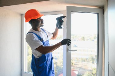 Evdeki oturma odasına plastik pencereler monte eden ya da ayarlayan işçi.