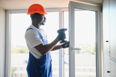 Evdeki oturma odasına plastik pencereler monte eden ya da ayarlayan işçi.