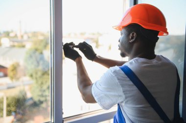 Evdeki oturma odasına plastik pencereler monte eden ya da ayarlayan işçi.