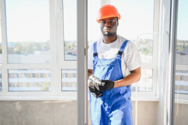 Tamirci, beyaz plastik pencereyi içeri ayarlıyor. İşçi, pencereyi onarmak için tornavida kullanıyor. ev ödevi.