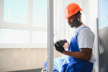 Yakışıklı genç adam yeni ev şantiyesine pencere takıyor..