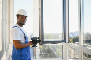 Evdeki oturma odasına plastik pencereler monte eden ya da ayarlayan işçi.