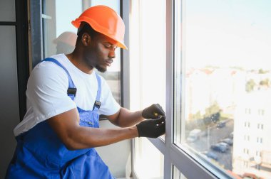 Evdeki oturma odasına plastik pencereler monte eden ya da ayarlayan işçi.