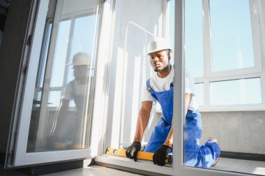 İnşaat alanındaki pencere kurulumunda çalışan erkek sanayi işçisi