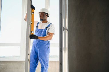 Yakışıklı genç adam yeni ev şantiyesine pencere takıyor..