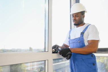 Yakışıklı genç adam yeni ev şantiyesine pencere takıyor..