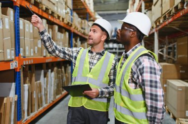 Two warehouse workers checking and controlling boxes in warehouse, Professional warehouse workers moving cardboard boxes by forklift stacker loader, Logistic and business export concept