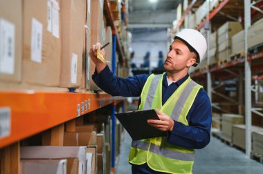 Büyük bir depo içinde clipboard onun listesine kontrol depo işçisi.