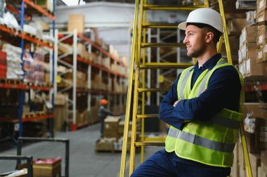 Nakliye müdürü depodaki tüm mal paletlerini onaylıyor, perakende mağazası için mal dağıtımı yapıyor. Çalışanlar üretim ürünlerinin kutularını karıştırıyor, notlar yolluyorlar..