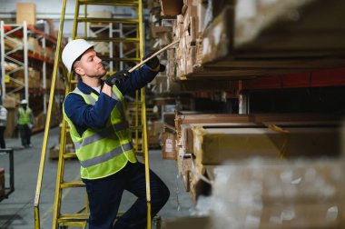 Nakliye müdürü depodaki tüm mal paletlerini onaylıyor, perakende mağazası için mal dağıtımı yapıyor. Çalışanlar üretim ürünlerinin kutularını karıştırıyor, notlar yolluyorlar..