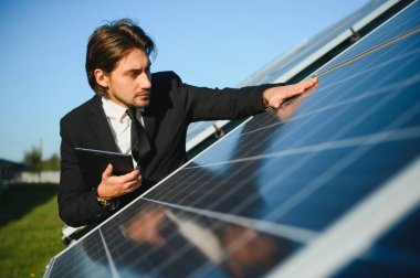 Başarılı bir işadamı ya da mühendis portresi güneş panellerini inceliyor. Yeşil enerji kavramı.