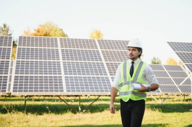 Güneş panellerinin yanında duran işadamı veya mühendis.