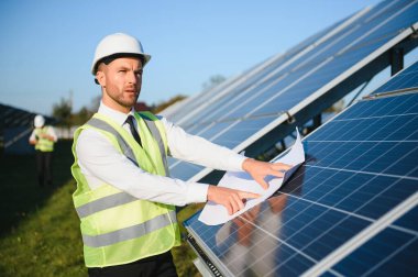 Solar power plant. Man standing near solar panels. Renewable energy.