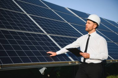 Güneş panellerinin yanında duran işadamı veya mühendis.