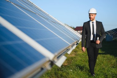 Başarılı bir işadamı ya da mühendis portresi güneş panellerini inceliyor. Yeşil enerji kavramı.