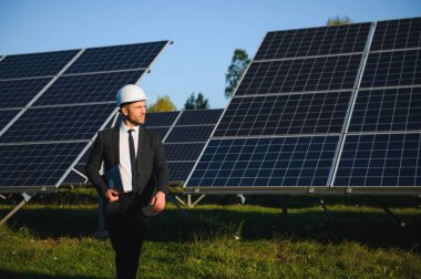 Solar power plant. Man standing near solar panels. Renewable energy.