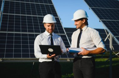 Güneş enerjisi bataryalarının yanındaki işadamı ve işçi.