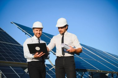 Güneş enerjisi bataryalarının yanındaki işadamı ve işçi.