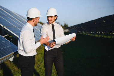 Güneş panellerinin yanında duran mühendislerin portresi.