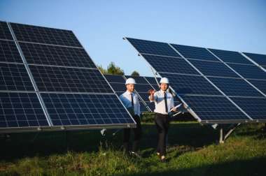Güneş çiftliği, güneş paneli ve iki mühendis sistemin işleyişini kontrol etmek için yürür, dünyanın enerjisini korumak için alternatif enerji, temiz enerji üretimi için fotovoltaik modül fikri.