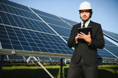 Solar power plant. Man standing near solar panels. Renewable energy.