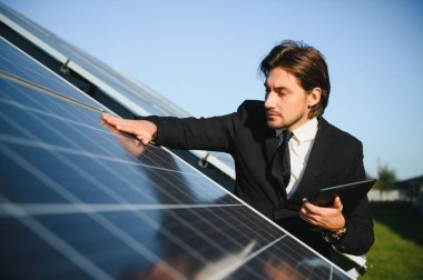 Güneş panellerinin yanında duran işadamı veya mühendis.