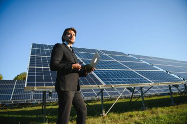 Güneş panellerini inceleyen bir iş adamının portresi. Yeşil enerjiye yatırım kavramı.