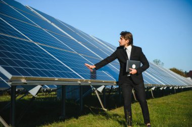 Solar power plant. Man standing near solar panels. Renewable energy.