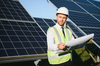 Güneş çiftliği, mühendis ile güneş paneli sistemin işleyişini kontrol eder, dünyanın enerjisini korumak için alternatif enerji, temiz enerji üretimi için fotovoltaik modül fikri.