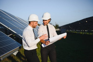 Güneş enerjisi bataryalarının yanındaki işadamı ve işçi.