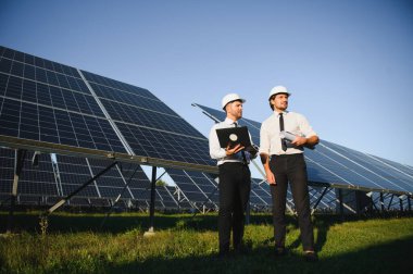 Güneş paneli çiftliği. İki Avrupalı mühendis güneş panellerini inceliyor. Güneş paneli çiftliğindeki işçiler.