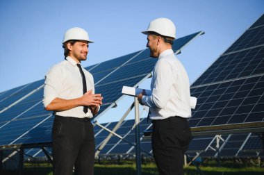 Güneş paneli çiftliği. İki Avrupalı mühendis güneş panellerini inceliyor. Güneş paneli çiftliğindeki işçiler.