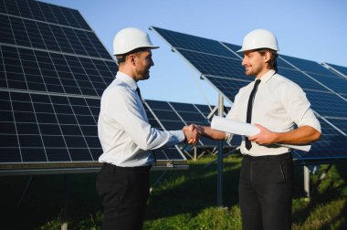 Güneş çiftliği, güneş paneli ve iki mühendis sistemin işleyişini kontrol etmek için yürür, dünyanın enerjisini korumak için alternatif enerji, temiz enerji üretimi için fotovoltaik modül fikri.