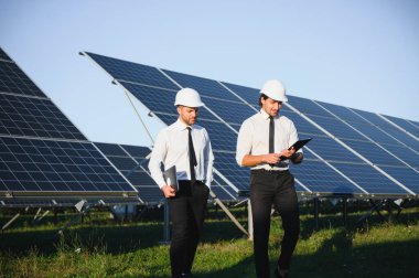 Güneş paneli çiftliği. İki Avrupalı mühendis güneş panellerini inceliyor. Güneş paneli çiftliğindeki işçiler.