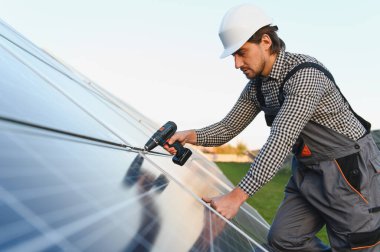 Güneşli bir günde güneş panelleri kuran güneş paneli teknisyeni.